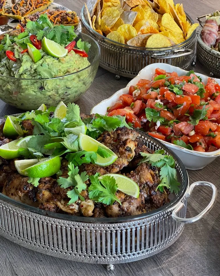 A served catering table with grilled meat, salsa and guacamole