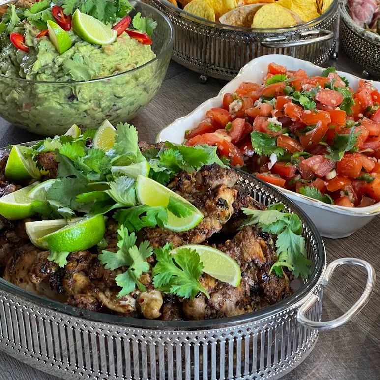 A served catering table with grilled meat, salsa and guacamole