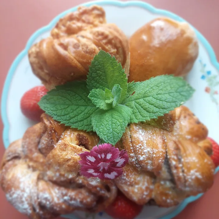 A plate of Meidi pastries with mint, a flower and strawberries